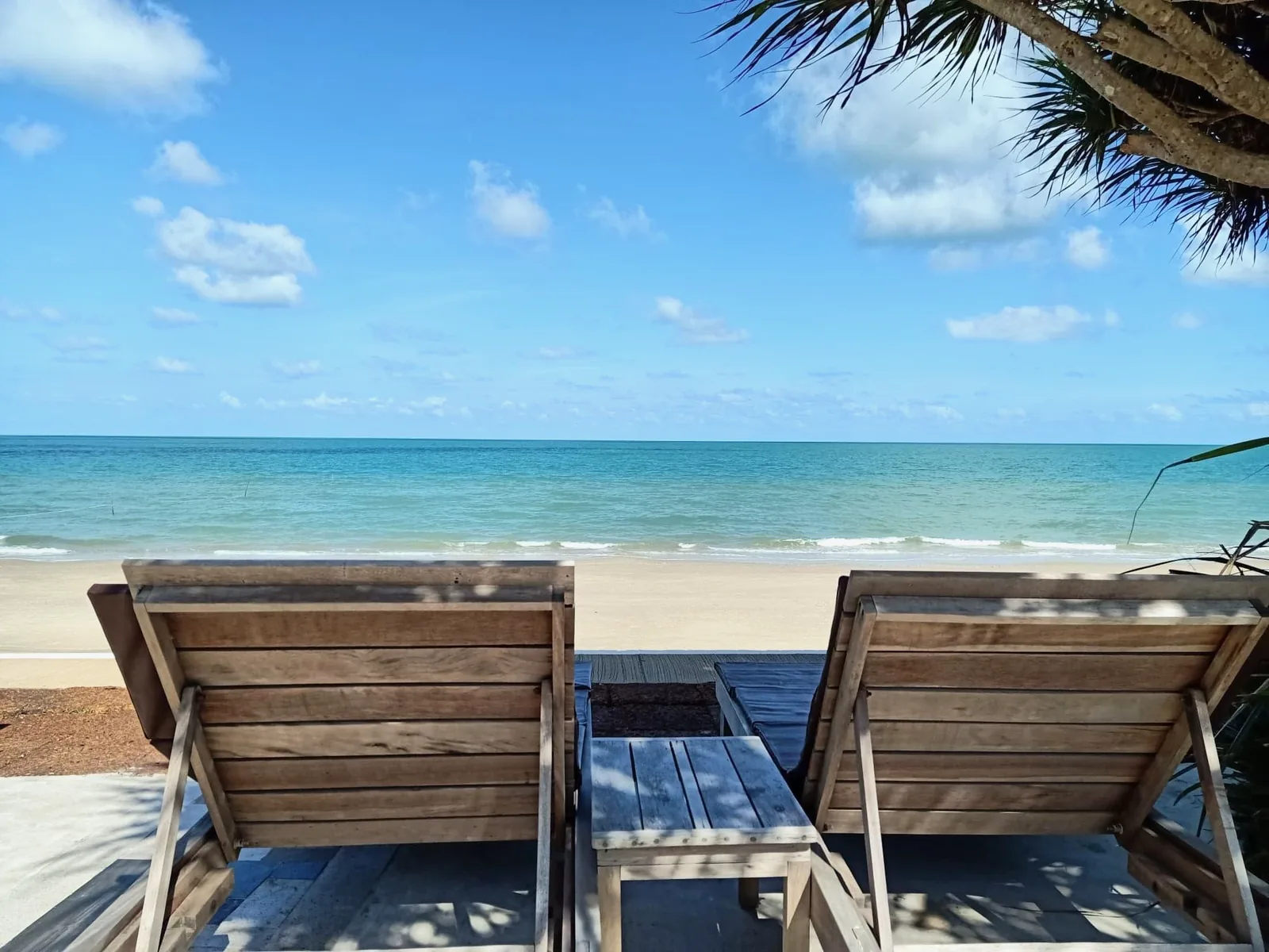 Two wooden sun loungers facing the turquoise sea on Nadan Beach